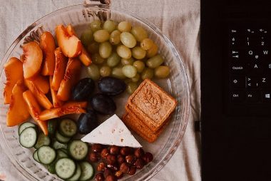 A delightful snack plate with fruits, cheese, and a laptop for a healthy lifestyle.